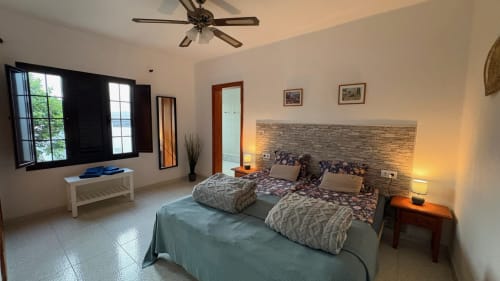 Double bedroom at Villa Estrella Polar in Tahiche with garden views, ceiling fan, and stone accent headboard