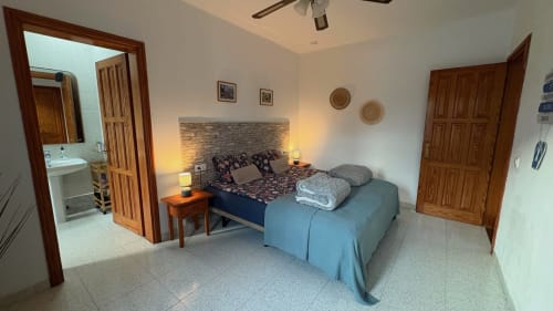 Double room with garden view at Villa Estrella Polar, Tahiche. Bed with stone headboard, wooden doors, ensuite bathroom,