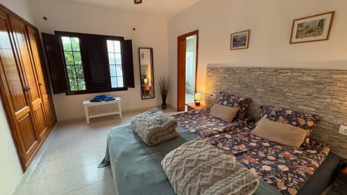 Double Room with Garden View at Villa Estrella Polar, Tahiche - two beds with floral bedding, stone accent wall, and garden