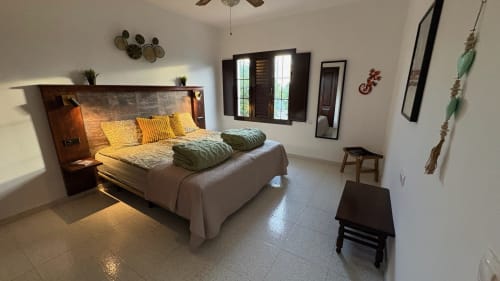 Spacious bedroom at Villa Estrella Polar with queen bed, yellow pillows, mountain views through windows, ceiling fan, and