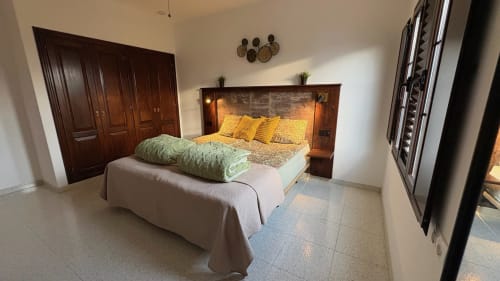 Spacious quadruple bedroom at Villa Estrella Polar in Tahiche with wooden headboard, yellow pillows, and mountain views