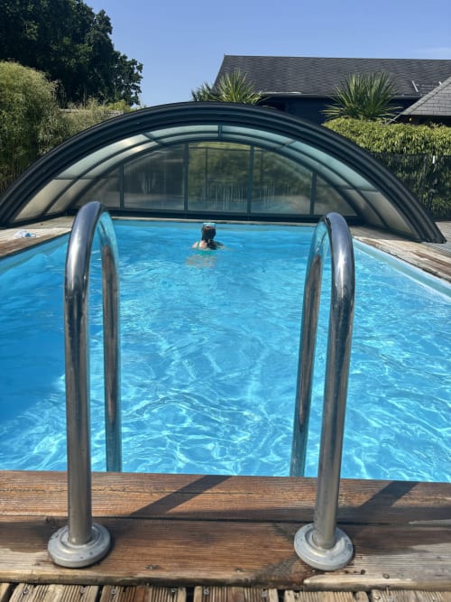 Piscine intérieure avec rampes métalliques aux Gîtes d'Armor en Tréguidel, France, eau bleue et dôme rétractable