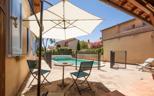 Shaded patio seating overlooking salt water pool at Villa Maison de Louis in Millau with terrace and garden views