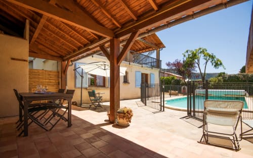 Rustic wooden pergola overlooking pool at La Conciergerie villa in Millau, outdoor terrace with dining area