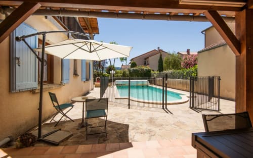 Millau villa terrace with pool view, cantilever umbrella, lounge chairs, and fenced swimming pool