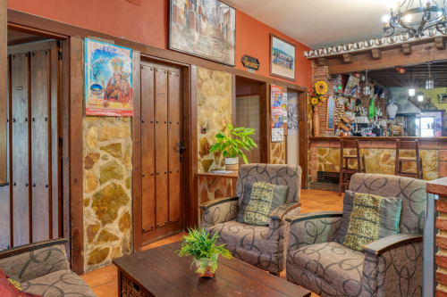 Hotel Balcón De Los Montés lobby in Colmenar with rustic stone walls, wooden doors, comfortable seating, and decorative