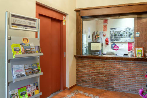 Hotel Balcón De Los Montés reception area with red elevator and brick counter desk in Colmenar