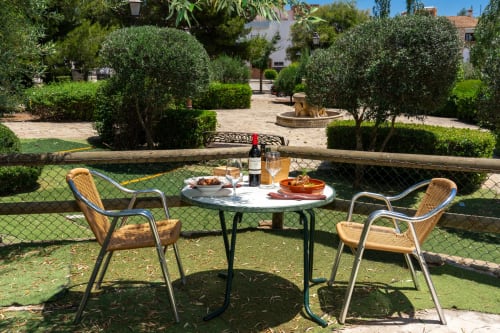 Outdoor dining setup at Hotel Balcón De Los Montés in Colmenar with wine and tapas overlooking lush gardens