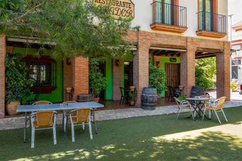 Hotel Balcón De Los Montés restaurant outdoor patio with green walls, dining tables, and brick architecture in Colmenar