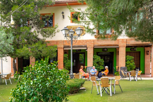 Hotel Balcón De Los Montés courtyard with guests dining on lawn, Colmenar Spain