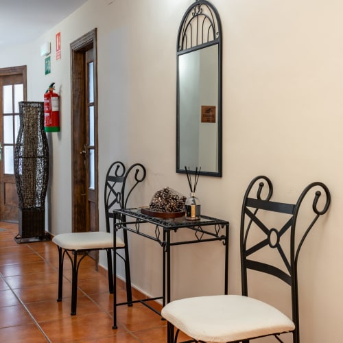 Hotel Balcón De Los Montés hallway with decorative wrought iron chairs, mirror, and side table in Colmenar