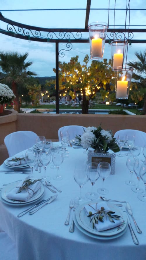Cena elegante al Clos Bb con tovaglia bianca, mise en place raffinata e candele sospese con vista su Saint-Cyr-sur-Mer
