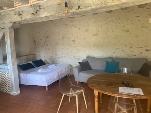Studio à l'Hôtel De La Bonnheure à Bracieux : lits jumeaux, canapé, table à manger et poutres apparentes rustiques.