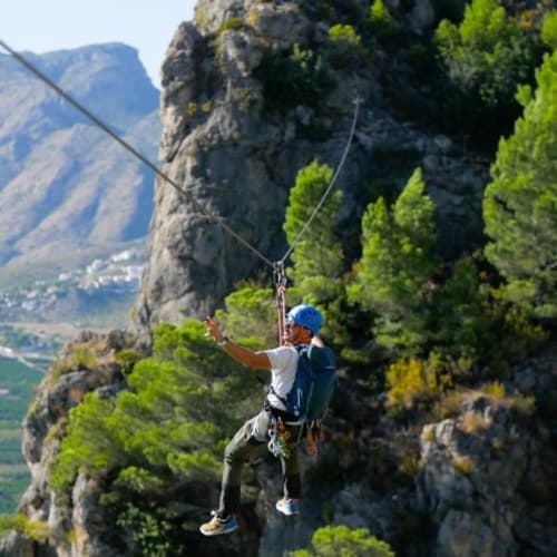 Escalador rappelando por acantilado cerca de Ròtova con vistas al valle