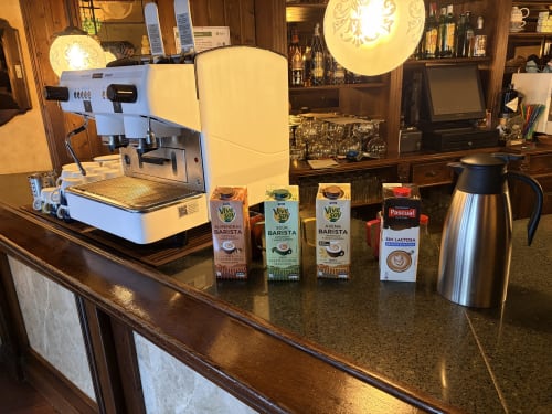 Máquina de espresso y cartones de leche en el bar de café Hostal Juan Carlos en Carboneras, España