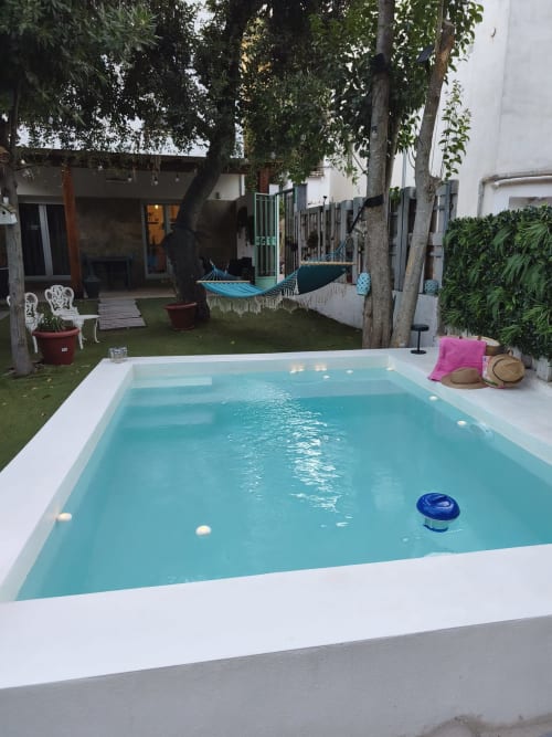 Piscina turquesa en jardín exuberante de La Vereda del Río Guadalquivir, Mogón España, con hamaca y zona de descanso