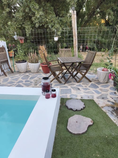 Patio trasero con borde de piscina, zona de descanso, plantas en macetas y césped sintético en apartamento Guadalquivir de Mogón