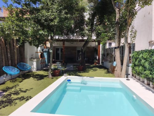 Piscina color turquesa en amplio jardín con patio, árboles de sombra, sillas azules y casita blanca en La Vereda