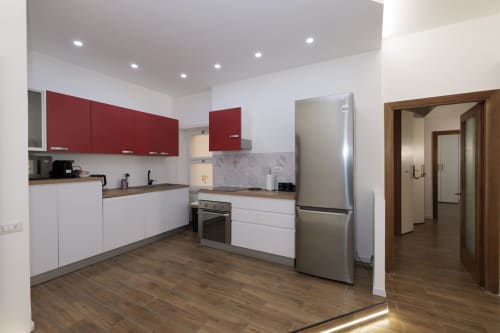 Cucina moderna con mobili rossi e bianchi, elettrodomestici in acciaio inossidabile, pavimenti in legno all'appartamento ViOletta, Lido di Ostia
