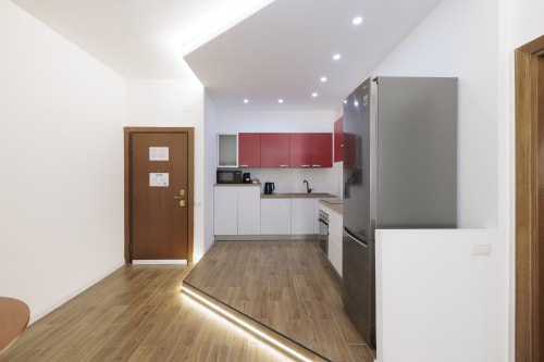 Cucina moderna nell'appartamento ViOletta, Lido di Ostia, con mobili rossi e bianchi, elettrodomestici in acciaio inox e