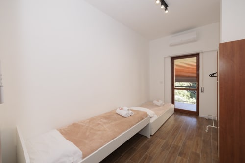 Letti gemelli in luminosa camera da letto con accesso al balcone e pavimento in legno, hotel ViOletta, Lido di Ostia