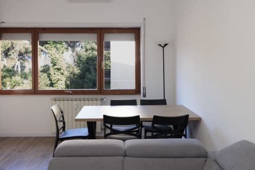 Zona living moderna dell'appartamento ViOletta a Lido di Ostia con tavolo, sedie nere, divano e grandi finestre con vista