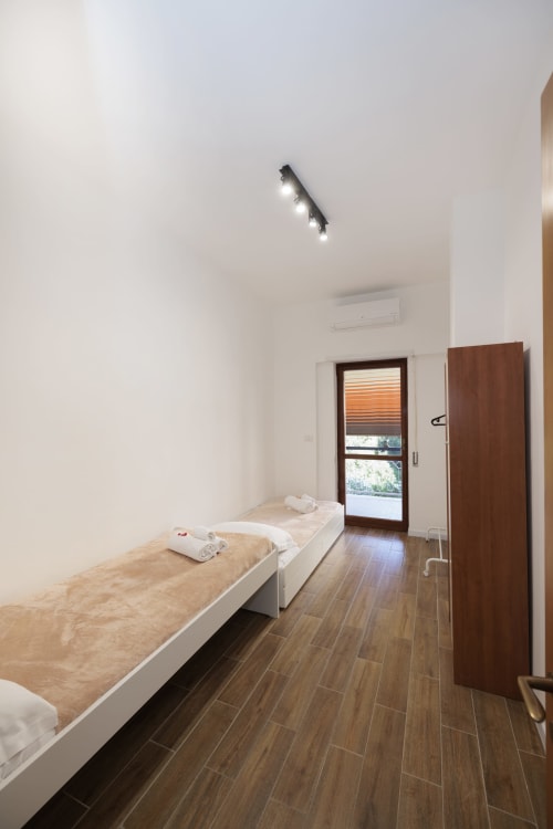 Camera moderna dell'appartamento ViOletta a Lido di Ostia con letto singolo, pavimento in legno e porta in vetro verso il balcone