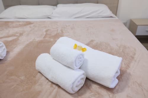 Asciugamani bianchi arrotolati con fiocco giallo decorativo sul letto dell'hotel ViOletta a Lido di Ostia