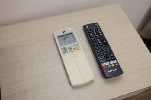 Due telecomandi sul tavolo di legno dell'appartamento ViOletta a Lido di Ostia - controlli per climatizzazione e televisione