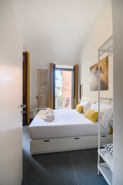 Camera Bright Design Suite ad Almatros a Sulmona con letto bianco, cuscini gialli, vista balcone e design minimalista moderno