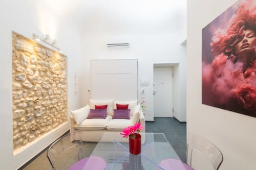Appartamento Peonia dell'hotel Almatros a Sulmona con zona living moderna, divano beige, fiore rosa, opere d'arte e dettagli in pietra
