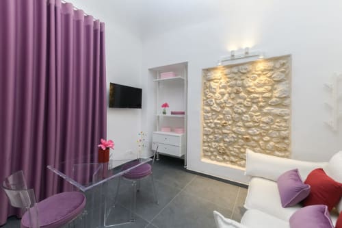 Appartamento Peonia dell'hotel Almatros a Sulmona con design moderno, tende viola, divano bianco e arte murale texturizzata