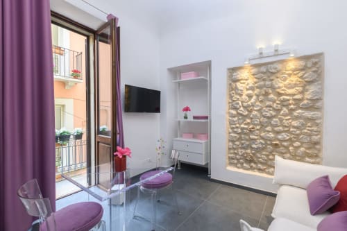 Moderno appartamento Almatros Sulmona con dettagli viola, accesso al balcone, TV e arte murale in pietra texture