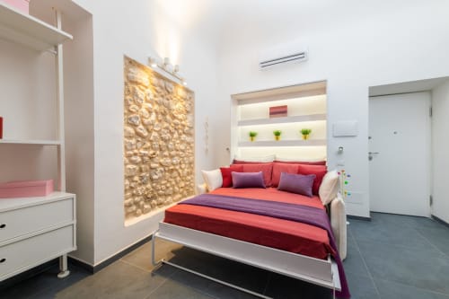Camera moderna dell'hotel Almatros a Sulmona con biancheria rossa, mobili bianchi e pannello decorativo dorato a parete