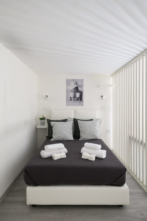 Camera moderna della Almatros Design Suite a Sulmona con letto nero, cuscini bianchi e asciugamani arrotolati