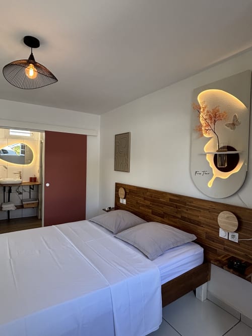 Modern bedroom at Domaine De Marly cottage with wooden bed, neon wall art, and contemporary lighting in Sainte-Anne