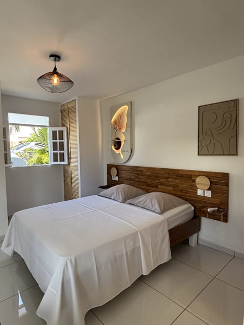 Chambre moderne du gîte Banane au Domaine De Marly, Sainte-Anne, avec tête de lit en bois et vue sur le jardin