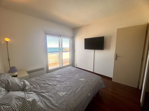 Spacieuse chambre avec literie rayée, TV écran plat et balcon panoramique avec vue sur la mer et le lagon de l'hôtel Barcaresa