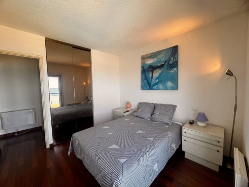Chambre moderne de l'appartement Barcaresa avec vue sur mer, linge de lit rayé, armoire miroir et décor côtier