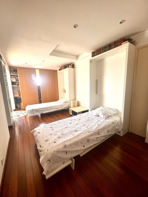 Chambre moderne de l'appartement Barcaresa avec deux lits, parquet, placards intégrés blanc et luminaires au plafond