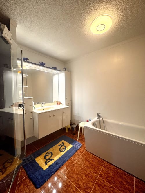 Salle de bain moderne de l'appartement Barcaresa avec meuble vasque, douche, baignoire et tapis de bain décoratif au Barcarès