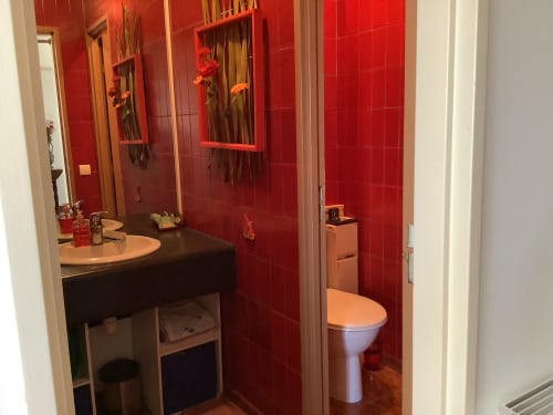 Salle de bain moderne aux carreaux rouges, double vasque avec miroirs et toilettes blanches à l'appartement Barcaresa, Le Barcarès