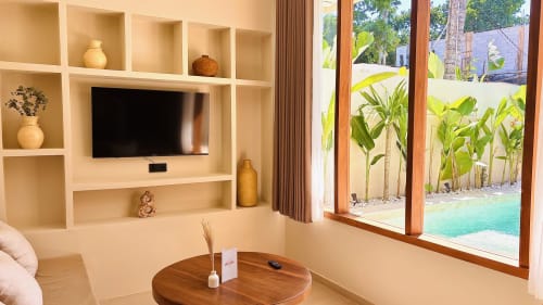 Modern villa lounge with built-in shelving, TV, and tropical garden views at Oasis Dune Villas Lombok