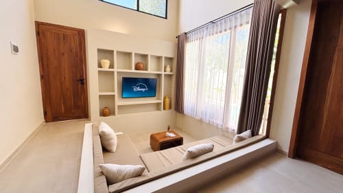 Sunken lounge in Oasis Dune Villas villa with TV, built-in shelving, wooden doors, and terrace access in Lombok
