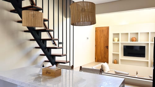 Modern villa living room at Oasis Dune Villas with black staircase, pendant lighting, white shelving, TV, and wooden door
