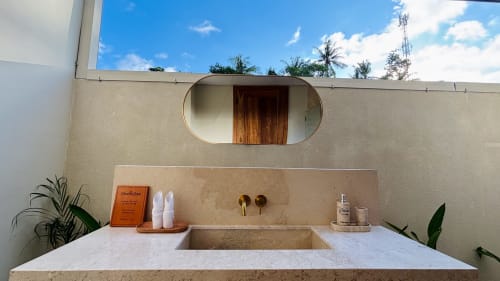 Modern bathroom at Oasis Dune Villas in Lombok with marble sink, rounded mirror, and tropical plants