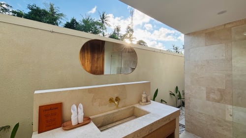 Modern outdoor bathroom at Oasis Dune Villas with curved mirror, marble sink, and tropical garden views in Lombok