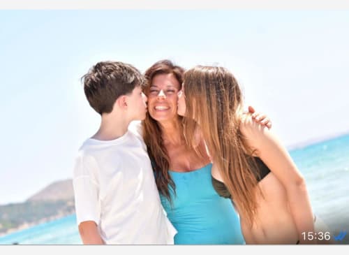 Donna e due bambini sorridenti sulla spiaggia dell'hotel Almatros a Sulmona con fondali di mare turchese