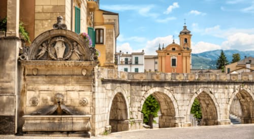 Ponte in pietra storico e fontana a Sulmona, Italia con cupola barocca visibile sullo sfondo