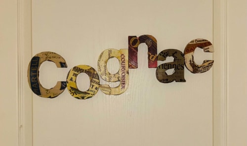Art mural décoratif épelant « Cognac » avec étiquettes de spiritueux vintage au Cadran Solaire, Courcelles